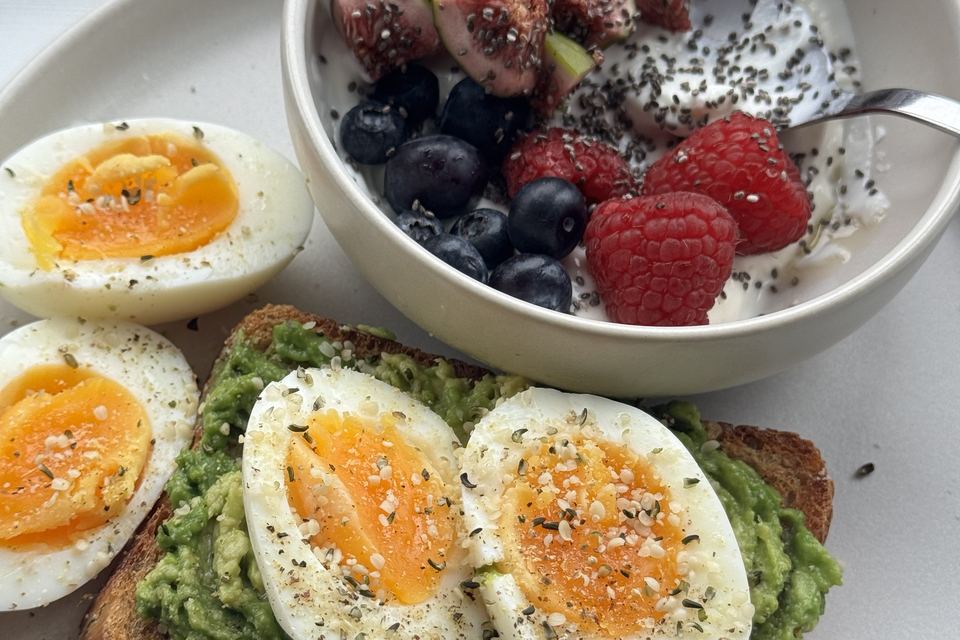 Boiled eggs on avocado toast with a yoghurt, fig and berry bowl