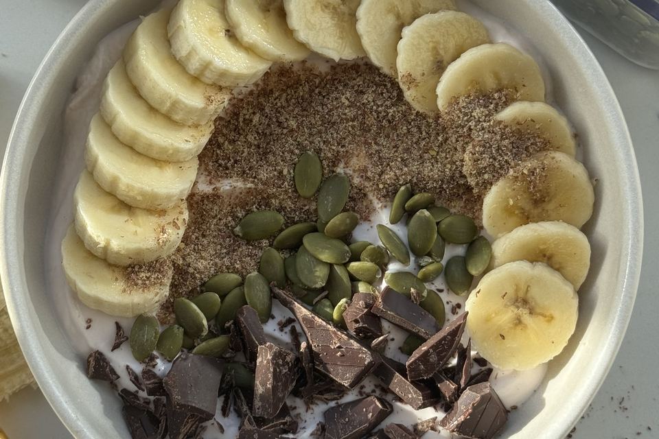 Yoghurt bowl with banana, flaxseed, pumpkin seeds and dark chocolate